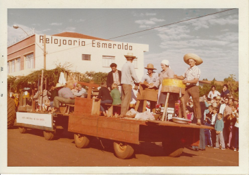 Carros alegórico do distrito de São Roque. 
No último veículo, vemos o professor Acádio Sachcht encenando a ministração de aulas para os primeiros alunos da localidade;  depois o pioneiro Carlos Fietz e esposa Aury (nascida Altmann, de lenço na cabeça), ele de chapéu de palha, movimentando o descascador de arroz; e os outros dois são os pioneiros Sebaldo Prieznitz (de chapéu grande) e Elizeu Lange. 