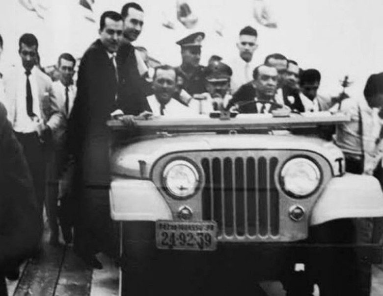Juscelino Kubitscheck dirigindo um jeep sobre a estrutura da construção da Ponte da Amizade, tendo ao seu lado o Presidente do Paranguai, Alfredo Stroessner. 
Imagem: Acervo Edulfo Torres / Waldir Guglielmi Salvan / Facebook.