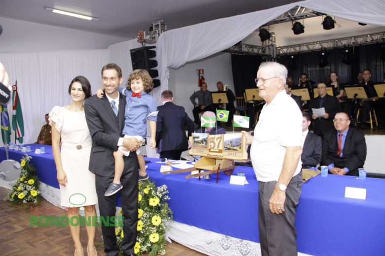 Márcio Andrei e esposa Josiane Laborde com o filho João Pedro e o artista e agricultor João Zimmermann, com a peça de arte produzida por ele em cima da Mesa de Honra.  
Imagem: Acervo Memória Rondonense - Crédito: Tioni de Oliveira