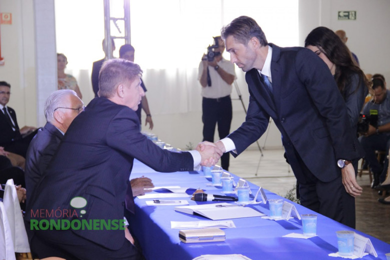 Márcio Andrei Rauber cumprimentando o 1º secretário da Câmara Municipal, vereador Nilson Hachmann. 
Iamgem: Acervo Memória Rondonense - Crédito: Tioni de Oliveira 