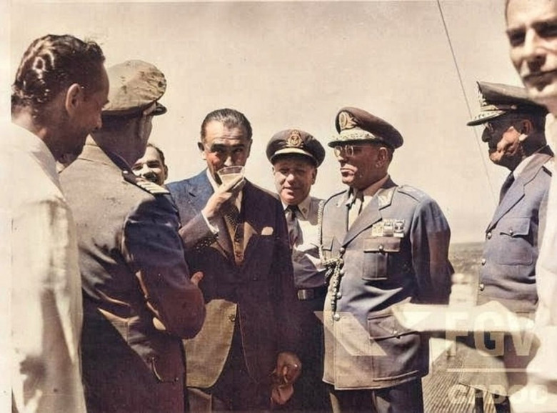 Presidente brasileiro Juscelino Kubitschek (de copo na mão) aguardando a chegada de seu colega paraguaio General Alfredo Stroessner. 
Imagem: Acervo Wagner Dias - Foz do Iguaçu / Facebook.
