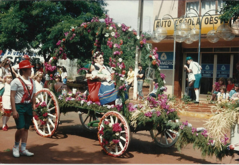 Sra. Alice Weirich desfilando com  dois boneco, representando seus dois filhos Clausio (em memória) e Clausia, primeiras crianças nascidas na atual cidade  de Marechal Cândido Rondon. 
A esquerda, o menino é Eduardo Weirich, filho de Ilo Weirich. 
Ao fundo, filmando o desfile é o fotógrafo Ademir Herrmann. 
Imagem: Acervo Família Weircih