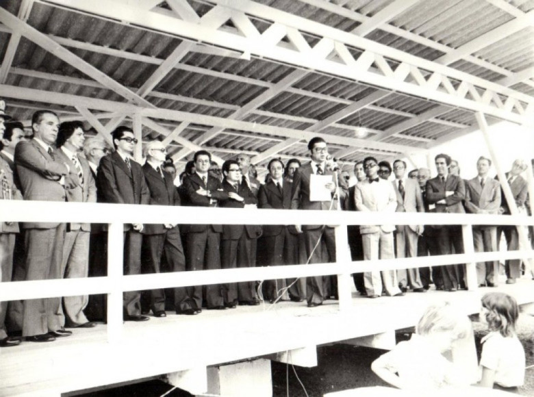 Outro instante do discurso do governador Jayme Canet Junior. À esquerda do governador: 1º - deputado estadual Egon Pudell  (atrás do locutor de gravata borboleta); 2º  e 3º - não identificados (ambos de óculos); 4º - Padre Antonio Darius - vigário da Matriz Católica Sagrado Coração de Jesus (de óculos, semi calvo); 5º - promotor de Justiça da comarca de Marechal Cândido Rondon, José Maria Bezerra Valente; 6º - pastor Jan Serfas, da Igreja Evangélica Congregacional (mãos cruzadas); e 7º - Pastor Mário Hort, da Igreja de Deus.