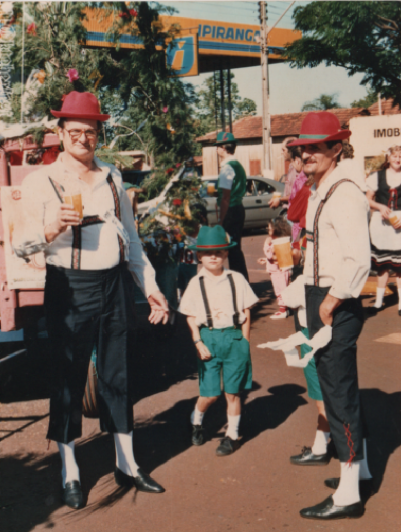 || Auro Becker (de copo na mão), administrador distrital de Iguiporã, junto com o morador Hildor Dreyer, na esquina da Avenida Rio Grande do Sul e a Rua D. João VI, aguardando a hora de iniciar o desfile da Oktoberfest 1989. 
Imagem: Acervo de Telci e Hildor Dreyer.