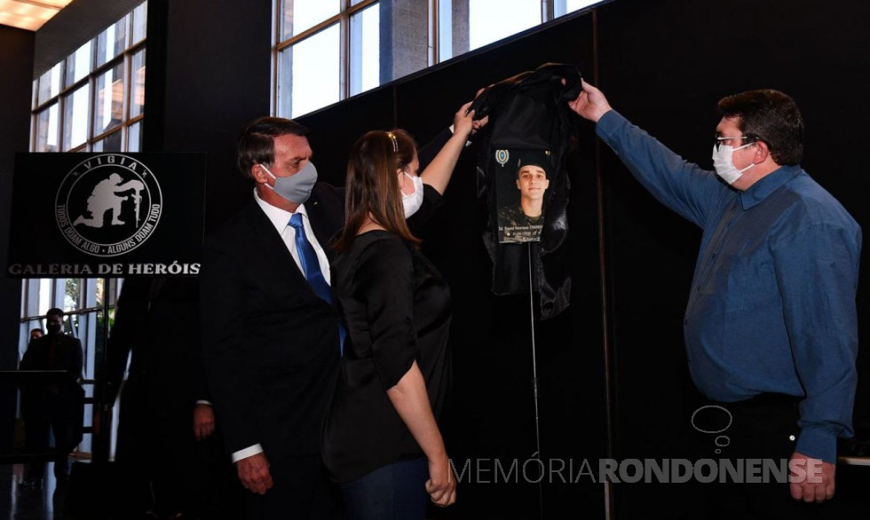 || Presidente Jair Bolsonaro descerrando a foto do soldado Daniel Henrique Trarbach Engelmann junto com os pais do jovem rondonense na Galeria do Heróis do Programa Vigia, em junho de 2020.
Imagem: Acervo Ministério da Justiça - FOTO 22 -