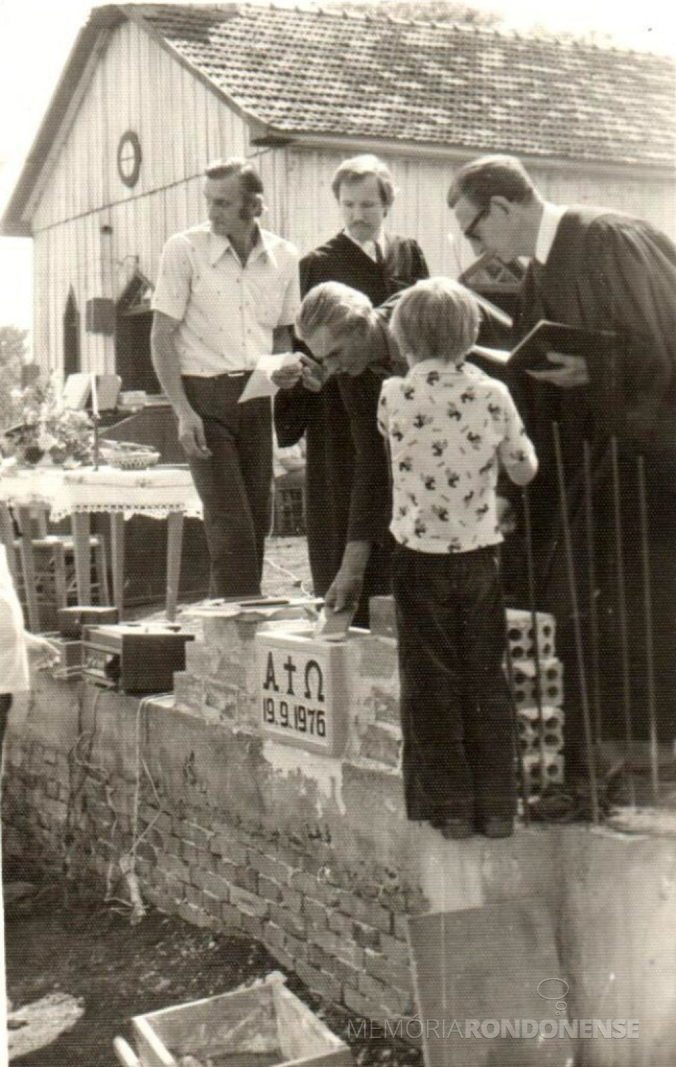 || Momento em que o presidente ou padrinho depositava documentos na canastra junto a base para a construção do novo templo da Comunidade Paz do distrito rondonense de Iguiporã, em setembro de 1976.
Da esquerda à direita: Jorge Figur, líder local da comunidade; pastor Oscar Lange eo pastor Guilherme Lüdke, da Congregação Cristo de Marechal Cândido Rondon.
A fundo, a primeira igreja em madeira.
Imagem: Acervo Valdecir Schons - FOTO 18 -