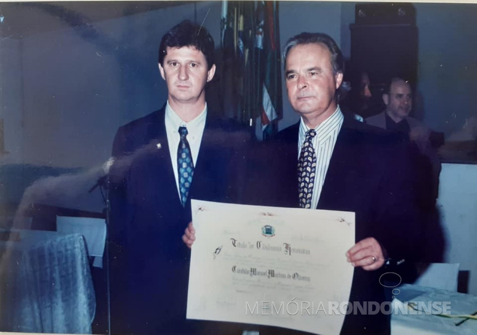 || Cândido Manoel Martins de Oliveira com o título de cidadão honorário de Marechal Cândido Rondon, ladeado pelo proponente da honraria, vereador Nilson Hachmann, em novembro de 1997.
Imagem: Acervo Arquivo pessoal do vereador - FOTO 10 -