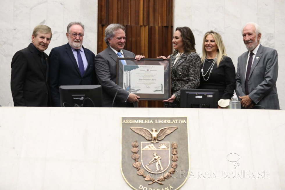 || Almirante Anatalício Risden Junior recebendo o título de Cidadão Honorário do Paraná das mãos da deputado estadual Maria Victória Barros, em abril de
Da esquerda à direita: deputado estadual Elio Lino Rusch (co-proponente da homenagem), deputado estadual Tercílio Turini (presidente da Sessão Solene), homeageado, deputada estadual co-proponente, ex-governador Cida Borghetti (do Conselho de Administração de Itaipu) e o Darci Piana, vice-goverandor do Paraná.
Imagem: Acervo Assembleia Legislativa do Estado do Paraná - FOTO 15 -