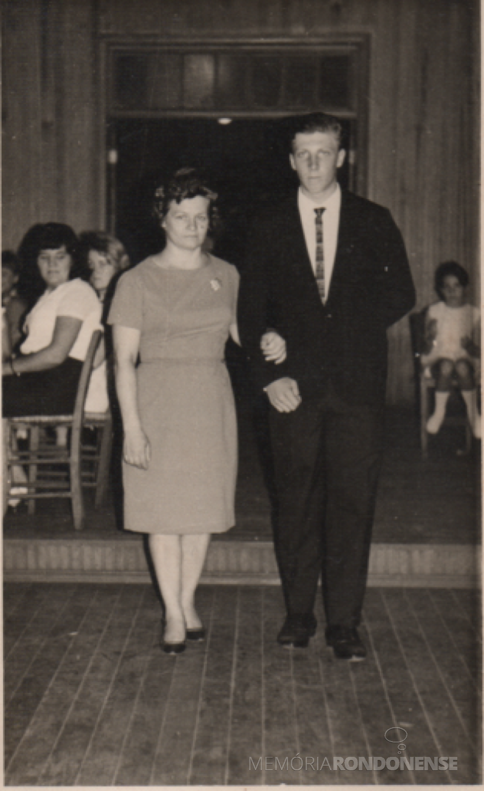 || Pioneira rondonense Selita Altmann entrando na antiga sede do Clube Aliança, de Marechal Cândido Rondon, com o filho Harraldo por ocasião da formatura ginasial dele no Colégio Luterano Rui Barbosa, em 1966.
Ela é falecida em novembro de 2016.
Imagem: Acervo de Harraldo Altmann - FOTO 6 -