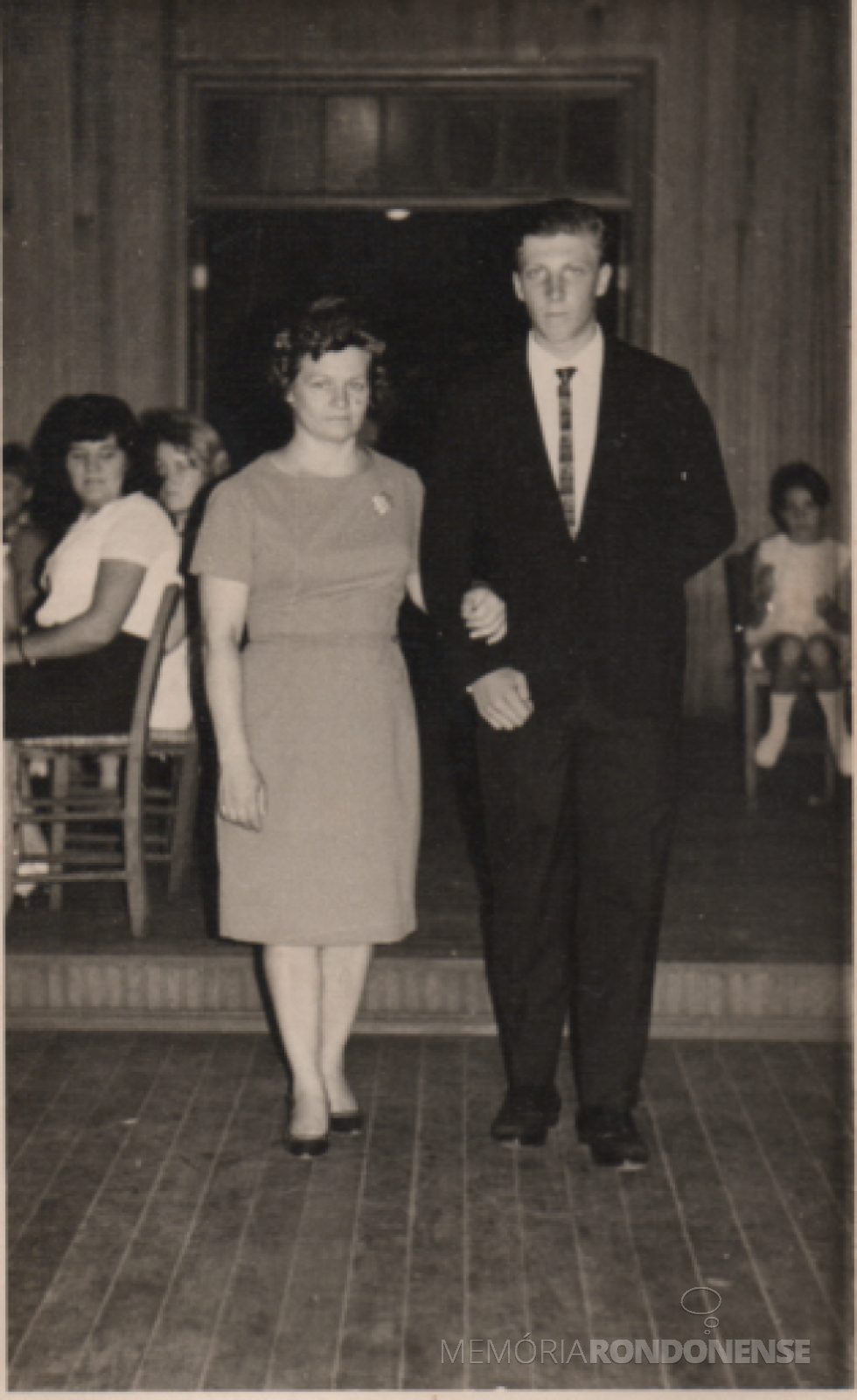 || Pioneira rondonense Selita Altmann entrando na antiga sede do Clube Aliança, de Marechal Cândido Rondon, com o filho Harraldo por ocasião da formatura ginasial dele  no Colégio Luterano Rui Barbosa, em 1966.
Ela é falecida em novembro de 2016.
Imagem: Acervo de Harraldo Altmann - FOTO 5 - 