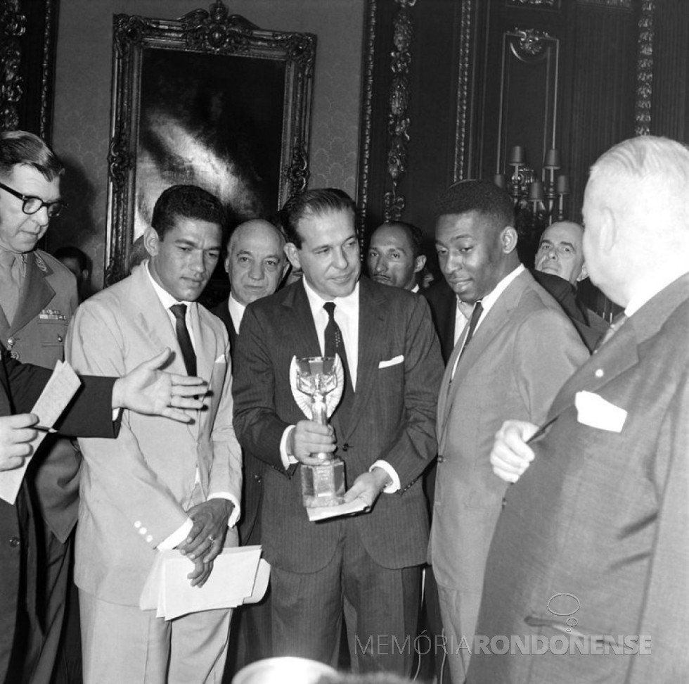 || João Belchior Marques Goulart, conhecido popularmente como Jango, o 14.º vice-presidente do Brasil, de 1956 a 1961, segura a Taça Jules Rimet levada ao Palácio pelos jogadores Garrincha (e) e Pelé.
Imagem: Acervo Monumentos do Rio de Janeiro & Brasil - FOTO 8 -