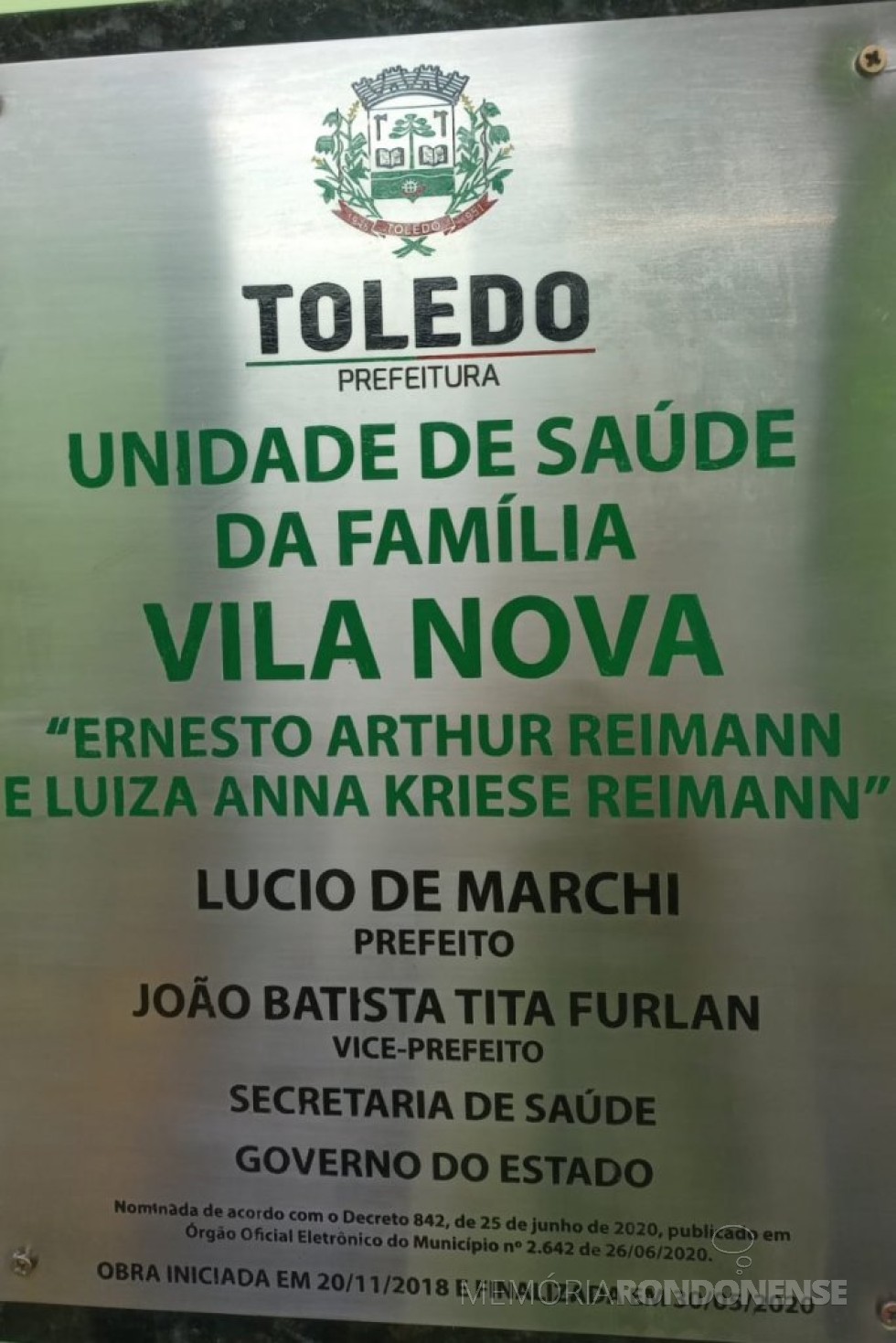 || Placa de designação da Unidade de Saúde da Família, localizada na sede distrital de Vila Nova (Toledo).
Imagem: Acervo Projeto Memória Rondonense - FOTO 5 - 