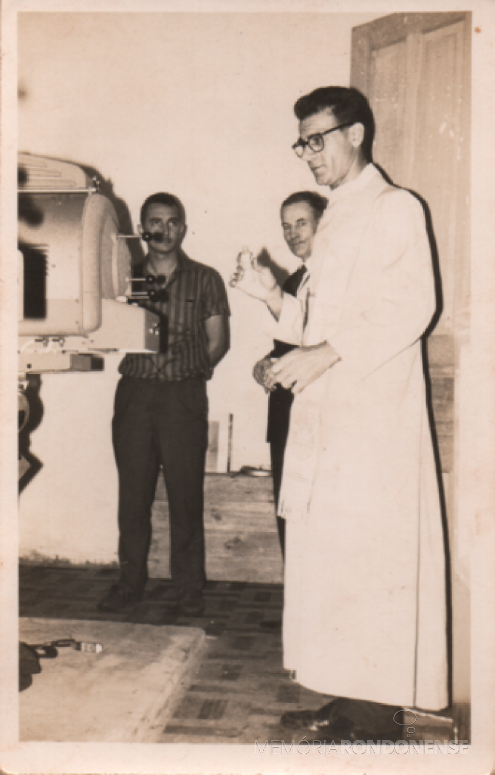 || Benção dos projetores do então Cine Ideal, de Marechal Cândido Rondon, pelo padre Cristiano Wiemann, pároco da Matriza Católica Sagrado Coração de Jesus, em janeiro de 1964.
Ao fundo, à esquerda, Raimundo Fagundes de Brito, sócio proprietário do cinema.
Imagem: Acervo Verner Fagundes de Brito - FOTO 1 -