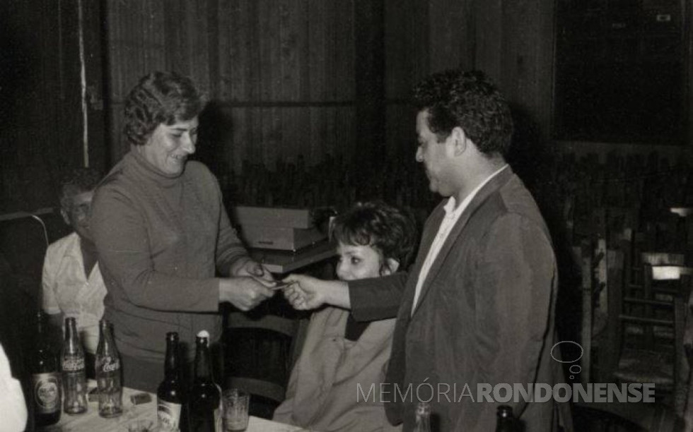 || Vereador Jossoé do Amaral Campos entregando um mimo para a primeira-dama do município, senhora Virica Poersch, durante o almoço para a formação da biblioteca pública. 
Imagem: Acervo Fundo Fotográfico de Marechal Cãndido Rondon. 
Imagem: Acervo Fundo Fotográfico de Marechal Cândido Rondon - FOTO 8 - 