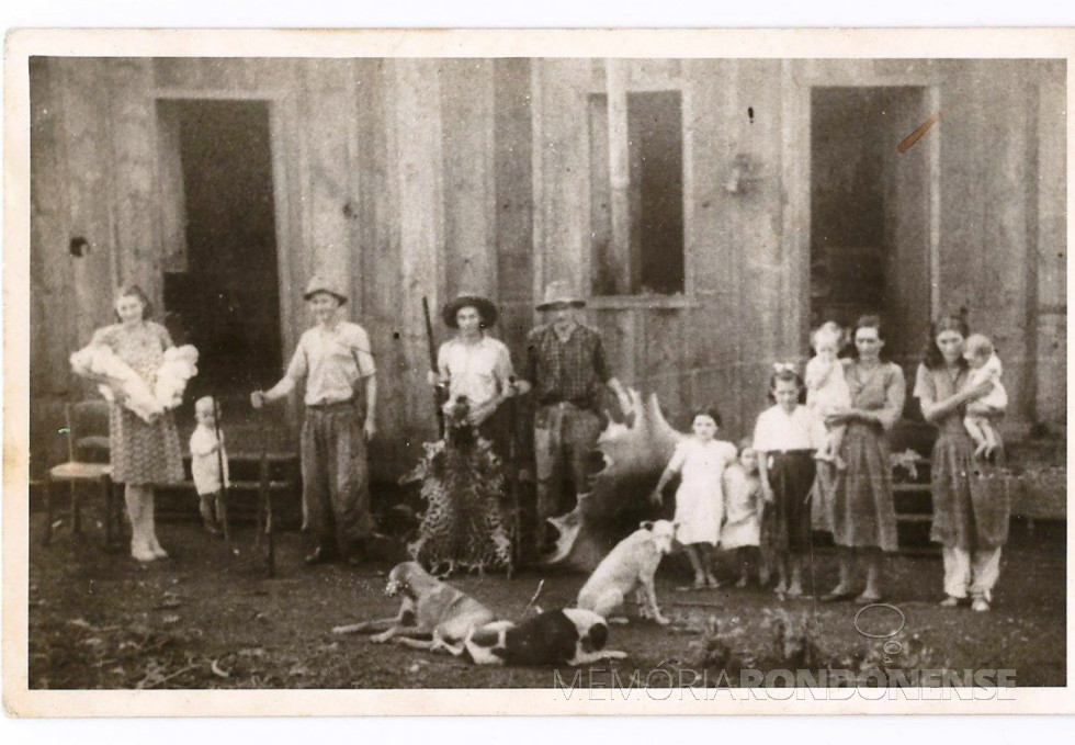|| Em frente ao barracão da Maripá, entre out.-nov./1950, onde moravam estas famílias. Da esquerda para a direita: WEIRICH, Alice com os gêmeos Cláucio (faleceu de crupe em dez./1950) e Cláucia, o menino Ilo e o pai Benno (os dois segurando espingardas), Lauro (segurando uma espingarda e uma pele de onça); GRIEBELER, Arlindo, as filhas Silda, Realda (tocando os borrachudos) e Brunilda, a esposa Hilda com a filha Luíza no colo; SCHEFLLER, Ida com um filho no colo (o marido e o outro filho haviam saído). Elaborado por Lia Dorotéa Pfluck, em 2000. FOTO Acervo de Alice Weirich, cedida em 1995.
PFLUCK, 2013, p. 109.
Imagem: Acervo Dr.a Dorotéa Pfluck - FOTO 1 -