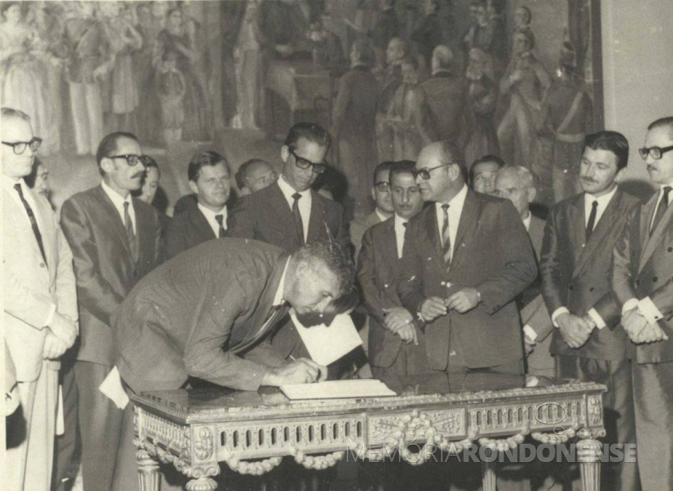 || Dealmo Selmiro Poersch assinando o termo de sua investidura como primeiro prefeito nomeado de Marechal Cândido Rondon, no Palácio Iguaçu, em Curitiba, em fevereiro de 1970.
Bem à direita: os deputados Ivo Tomazoni e Roberto Wypich.
Imagem: Acervo Fundo Fotográfico de Marechal Cândido Rondon - FOTO 1 -