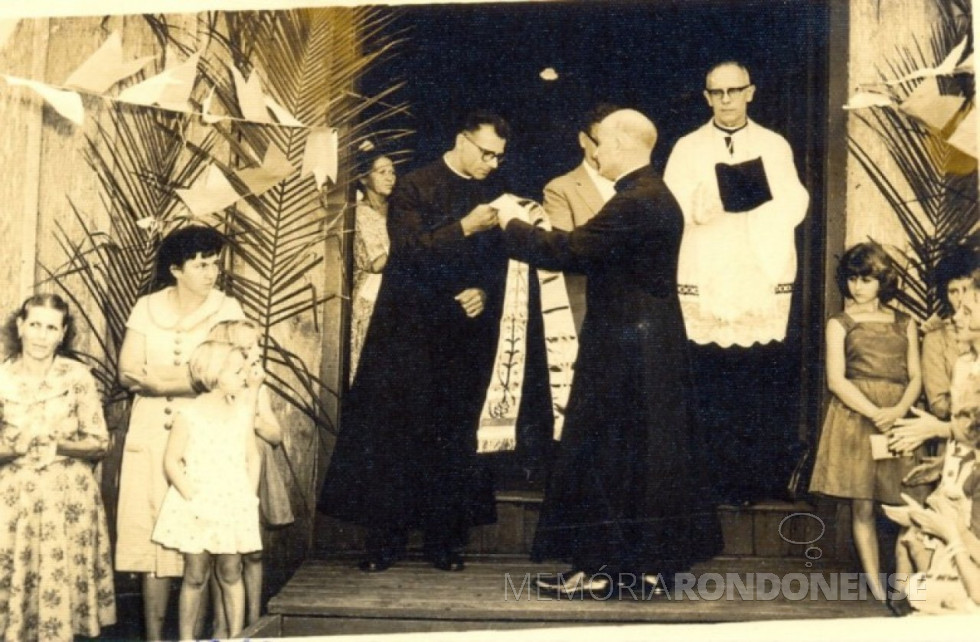 || Padre Cristiano Weimann SVD recebendo a estola, simbolo da autoridade sacerdotal, de seu confrade Aloísio Baumeister que vinha atendendo a paróquia em substituição o padre João Assmann SVD, que lhe antecedeu como vigário da Paróquia Sagrado Coração de Jesus, da sede municipal de Marechal Rondon. Imagem: Acervo Memória Rondonense - FOTO 1 -