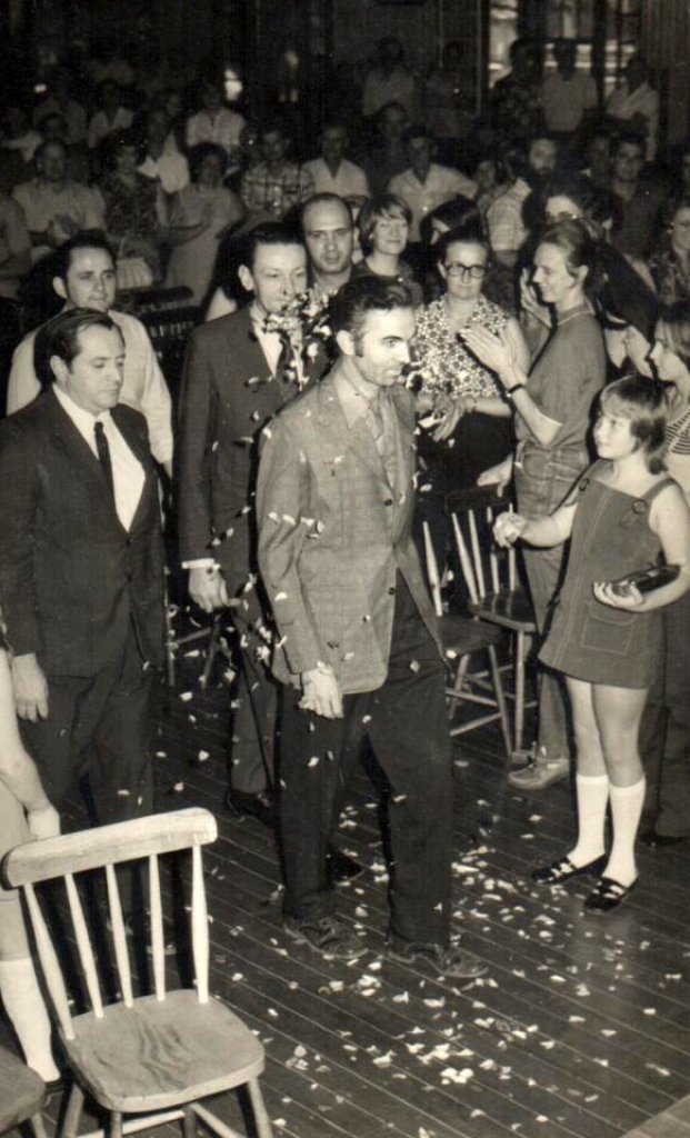 || Almiro Bauermann recepcionado na entrada do salão do Clube Aliança, seguido pelos vereadores Salvino Wanderlinde (de paletó escuro), Noori Pooter (de camisa branca) e Ilvo Grellmann, a direita, (de paletó escuro). 
Imagem: Acervo Almiro Bauermann - FOTO 8 -