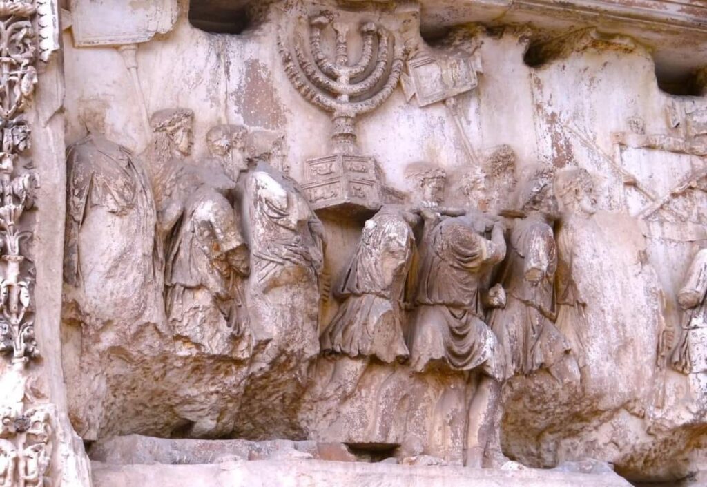 || Alto relevo no interior do Arco de Tito em Roma. A escultura enaltece a destruição de Jerusalém e do Templo pelos romanos. Observe-se a menorah - candelabro sagrado do Templo -, sendo levado em triunfo pelos invasores .
Imagem: Acervo pessoal do autor - FOTO 19-