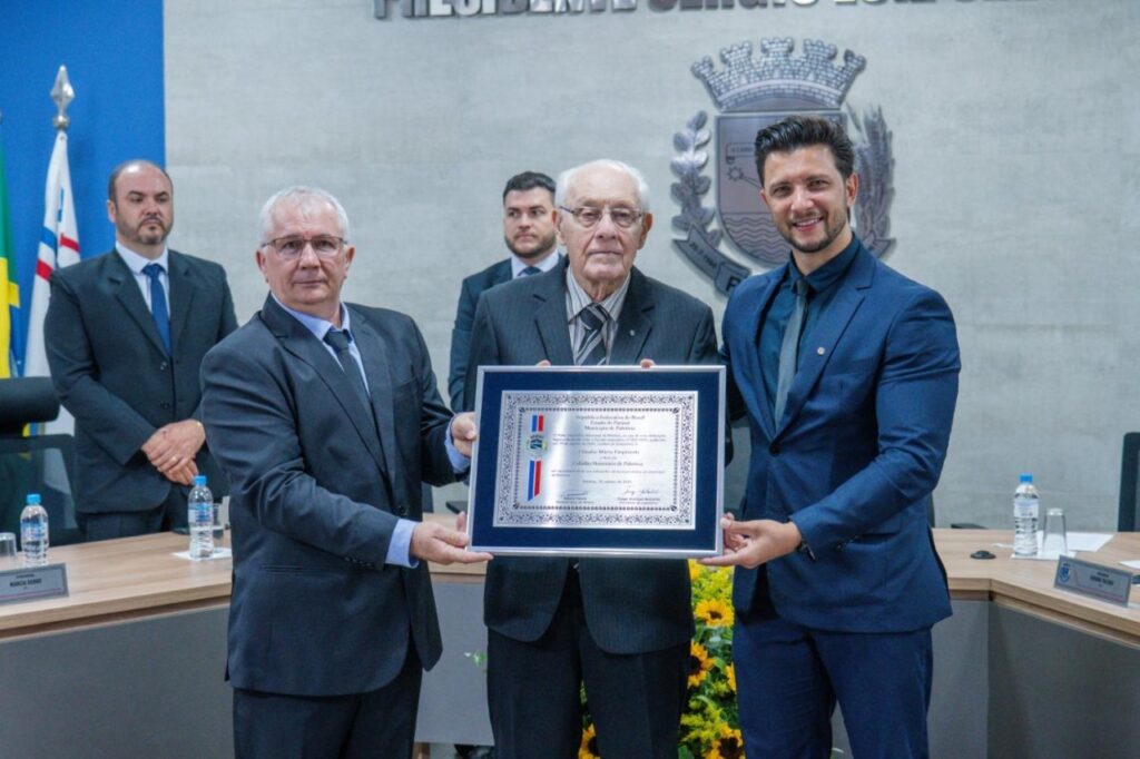 || Engenheiro agrônomo Cláudio Mário Empinotti com o título de Cidadão Honorário de Palotina, recebido das mãos do verador Ademir Paludo (e) e do prefeito municipal da cidade, Rodrigo Ribeiro.
Imagem: Acervo da Câmara de Vereadores - FOTO 32 -