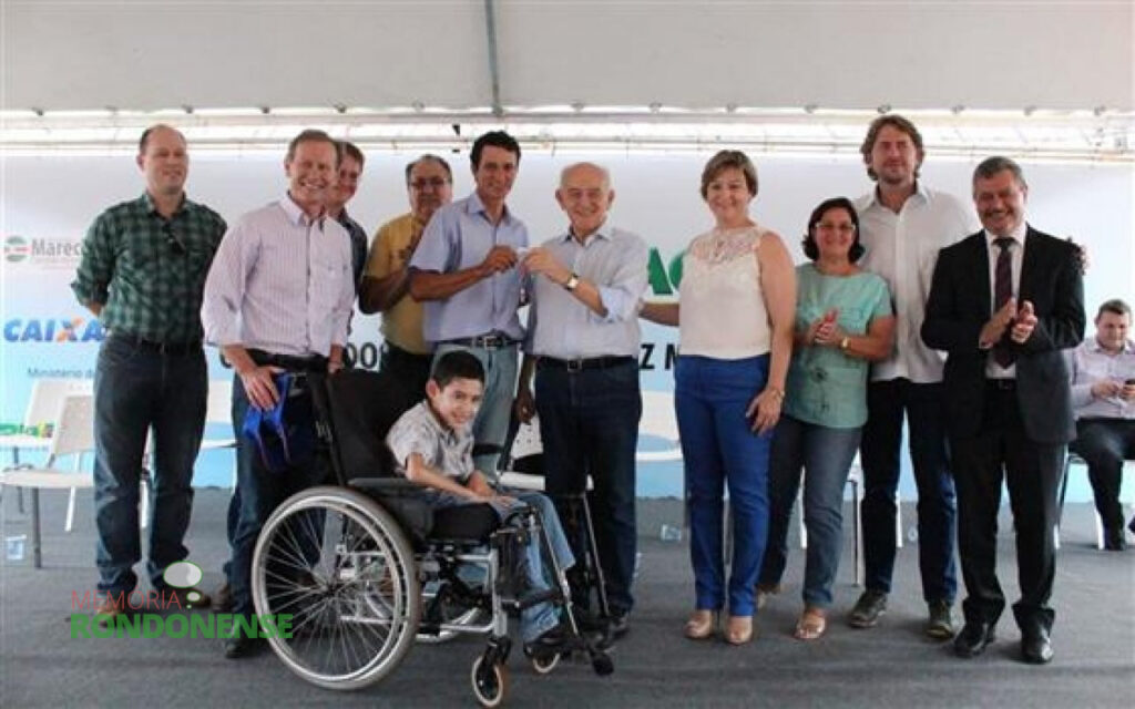 O mutuário Edilson Luiz Ferreira com o filho recebendo as chaves de sua moradia no Loteamento Recanto Feliz do ministro Manoel Dias. 
Da esquerda para a direita: 1º - Christain Guenther, secretário de Governo de Marechal Cândido Rondon; 2º - Moacir Froelich,  prefeito municipal, 3º engenheiro-civil Wild; 4º - não identificado; 5º - Edilson Luiz Ferreira recebendo as chaves; 6º - ministro Manoel Dias; 7º - Cleonice Froelich, secretária municipal de Assistência Social; 8º - esposa do vice-prefeito Silvestre Cottica; 9º -  deputado federal Zeca Dirceu; e 10º - não identificado. 
Imagem: Acervo O Presente