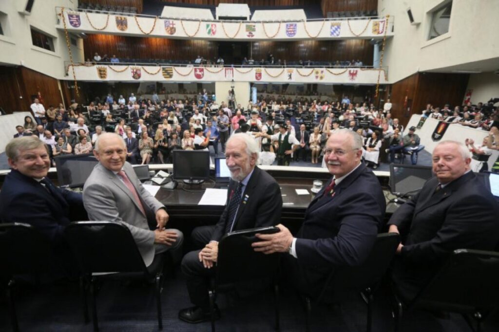 || Outra vista da composição da mesa oficial da sessão solene dos 190 anos da imigração Alemã no Paraná.
Da esquerda à direita: deputado estadual Elio Lino Rusch, deputado estadual Ademar Traiano, vice-governador Darci Piana, ex-deputado estadual Orlando Pessuti e cônsul honorário da Alemanha em Curitiba, Andreas Hoffrichter.
Imagem: Acervo Alep - crédito de Orlando Kissner - FOTO 19 -